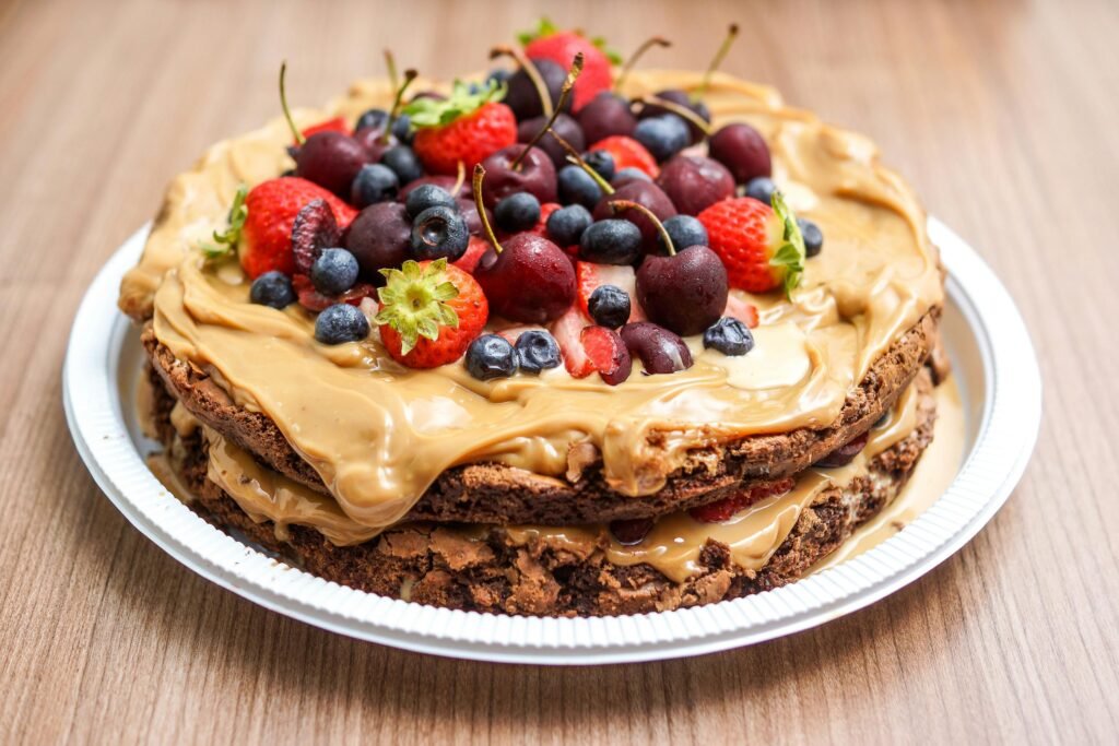 Delicious layered chocolate cake with fresh berries and peanut butter cream on a plate.