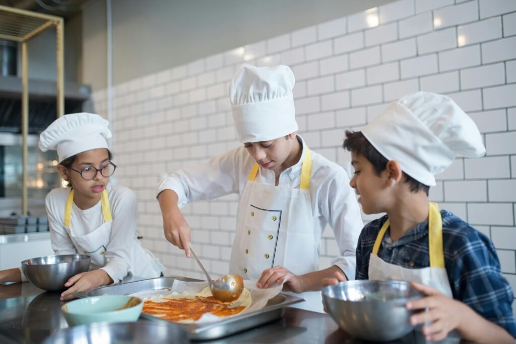Young aspiring chefs in Portugal make pizza, spreading tomato sauce enthusiastically in a fun cooking class.